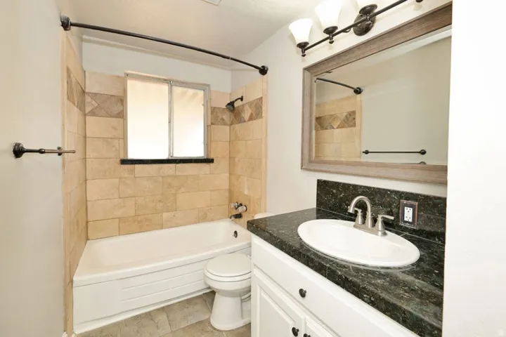 Bathroom featuring a vanity with a dark speckled countertop, an undermount sink, and a framed mirror