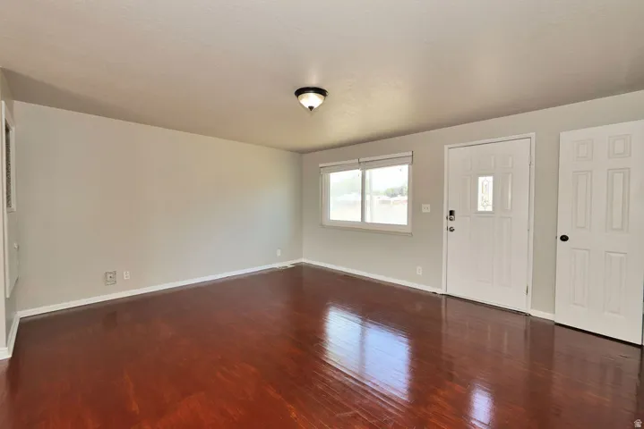 Spacious interior with rich wood-finish flooring, light neutral walls, and white trim