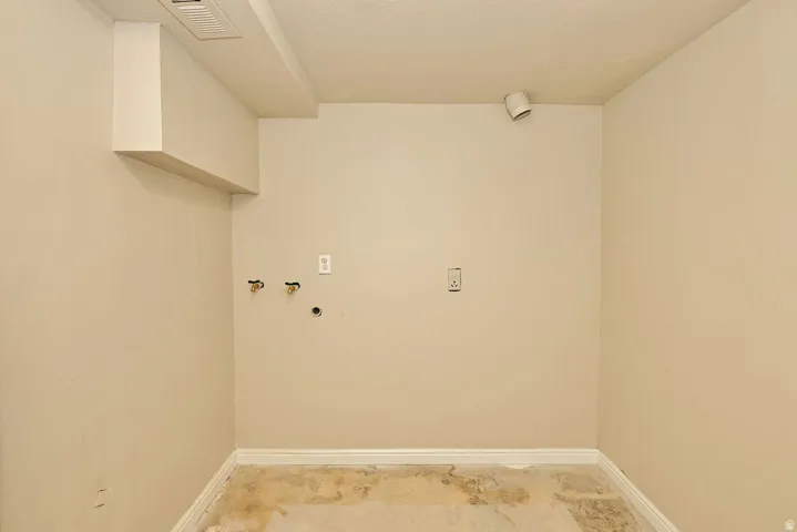 Utility area featuring wall-mounted water hookups, dedicated electrical outlets, and track lighting