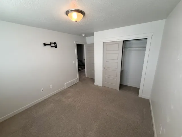 Neutral-toned carpeted room featuring a ceiling-mounted light fixture, white painted walls, and white trim