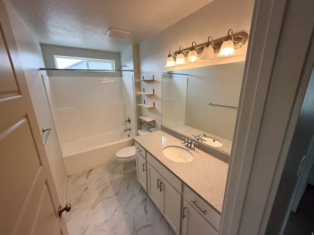 Bathroom featuring a double vanity with light speckled countertops, white cabinetry, and undermount sinks