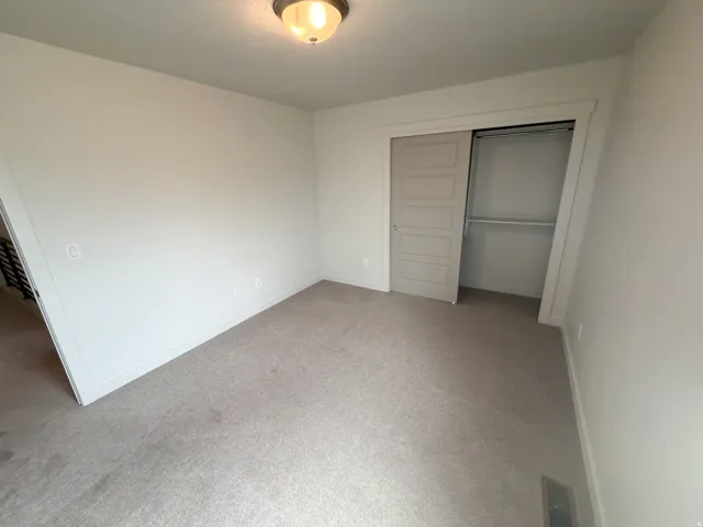 Carpeted room with a sliding closet door and an overhead flush mount light fixture