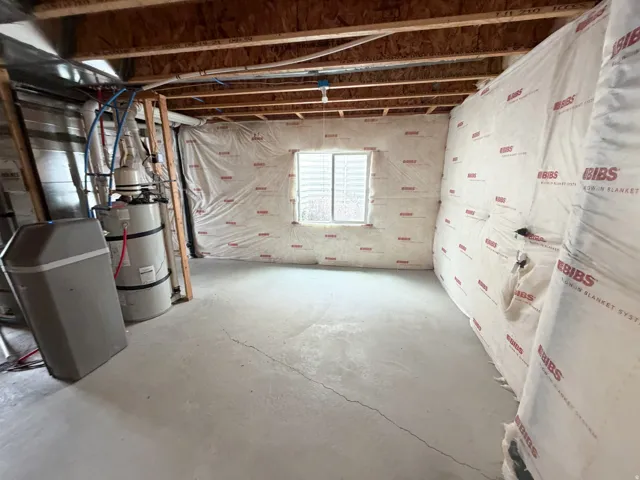 Unfinished basement featuring exposed ceiling joists, concrete flooring, and insulated perimeter walls