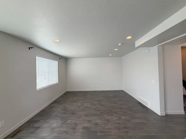 Spacious room featuring wood-finish flooring, recessed lighting, and a window with blinds