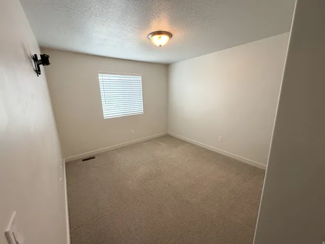 Carpeted room with neutral wall tones and a single window featuring horizontal blinds