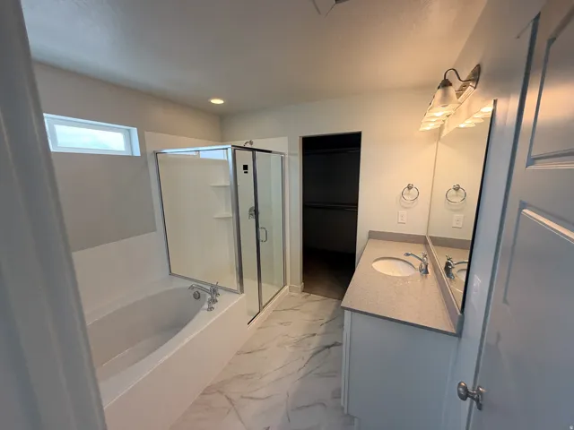 Bathroom featuring a glass-enclosed shower, a separate built-in bathtub, and a vanity with a light-colored countertop