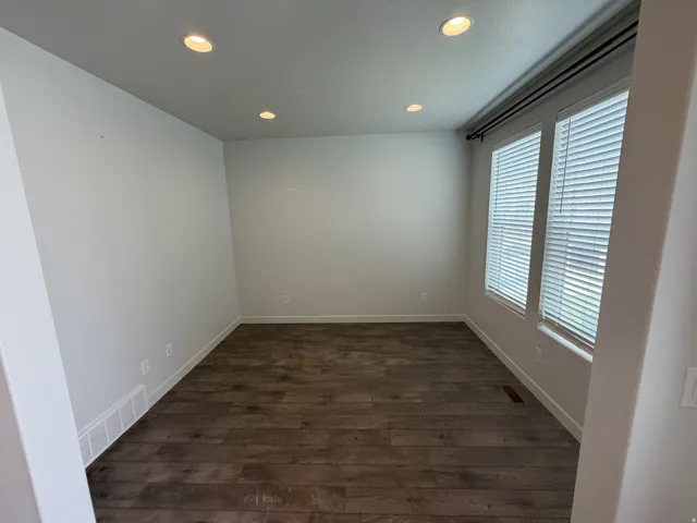 Room featuring wood-finish flooring, recessed lighting, and two windows with horizontal blinds