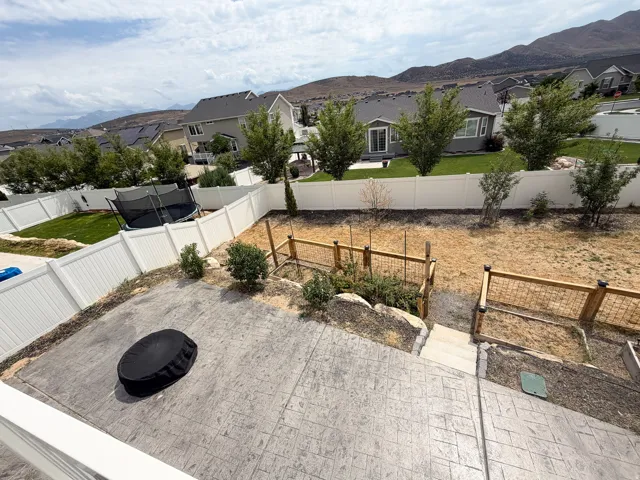 Expansive outdoor space featuring a stamped concrete patio, tiered landscaping with steps, and a white privacy fence