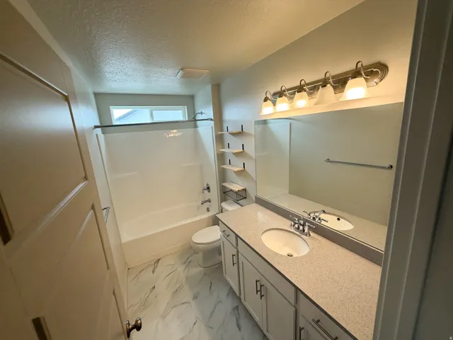 Bathroom featuring a double vanity with stone countertops, undermount sinks, and a full-width mirror with overhead five-light fixture
