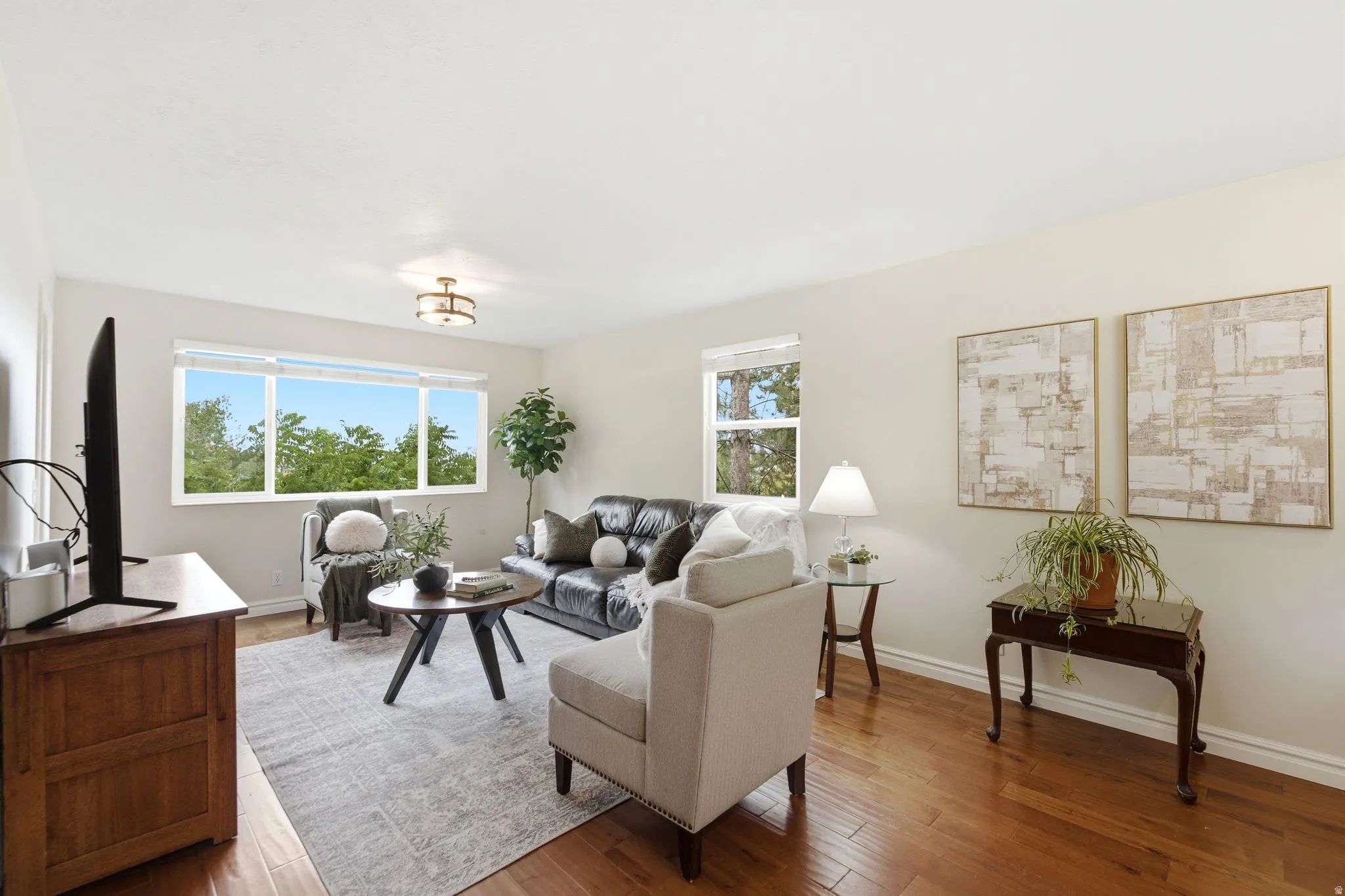 Bright living area with wood-finish flooring, a large multi-pane window, and recessed lighting
