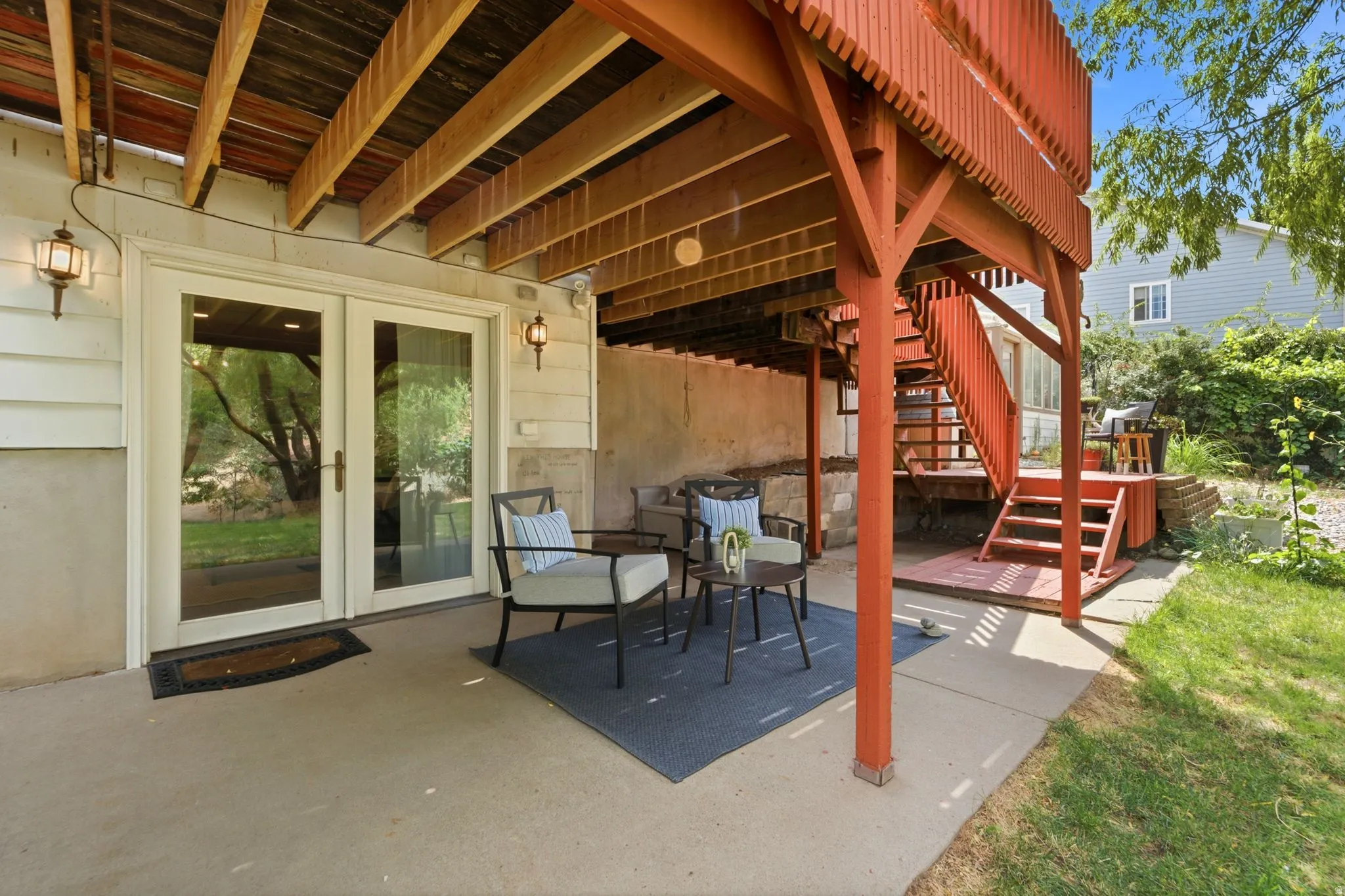 Patio area featuring concrete flooring, white siding, and wall-mounted exterior lighting