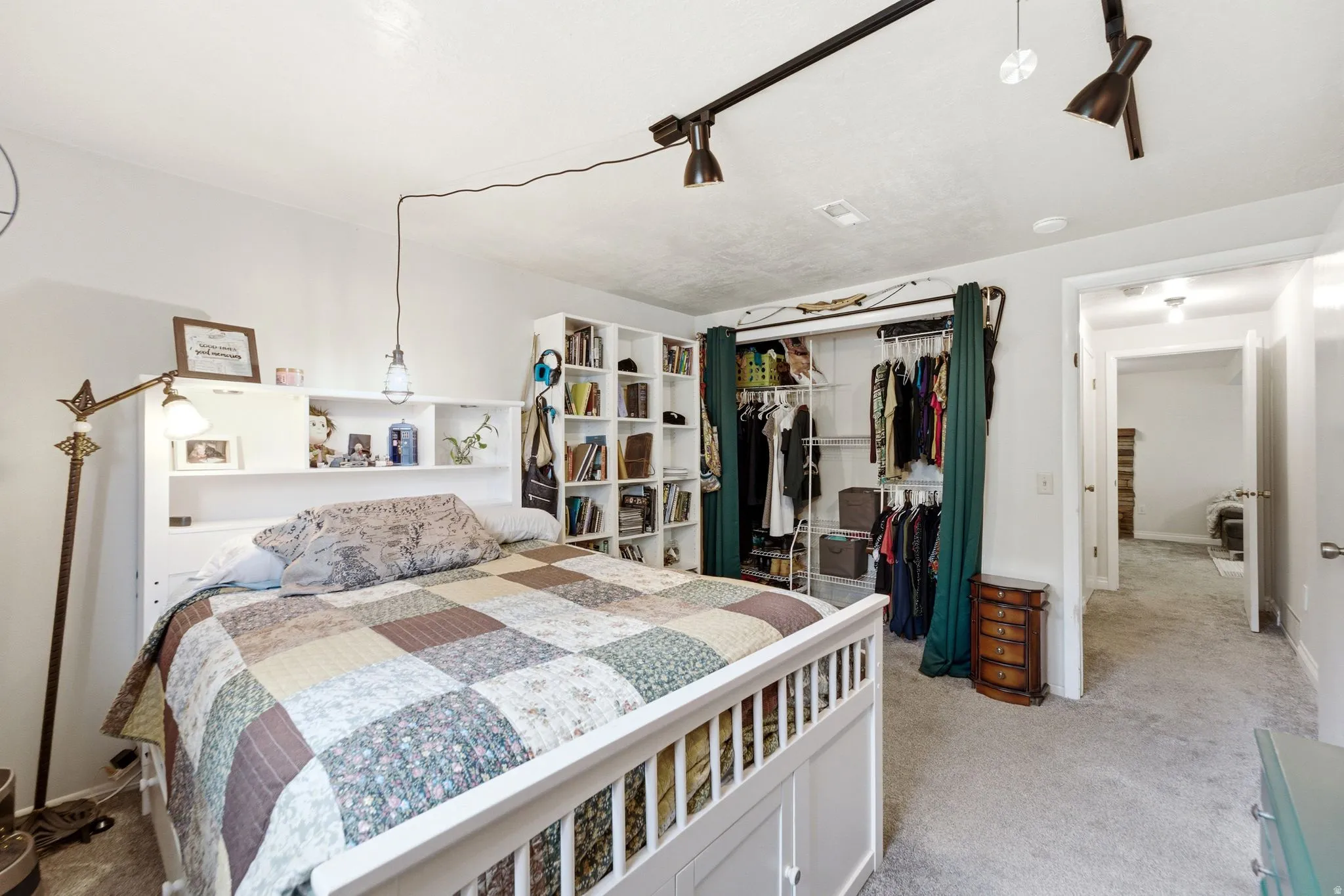 Carpeted room featuring track lighting and a built-in shelving unit