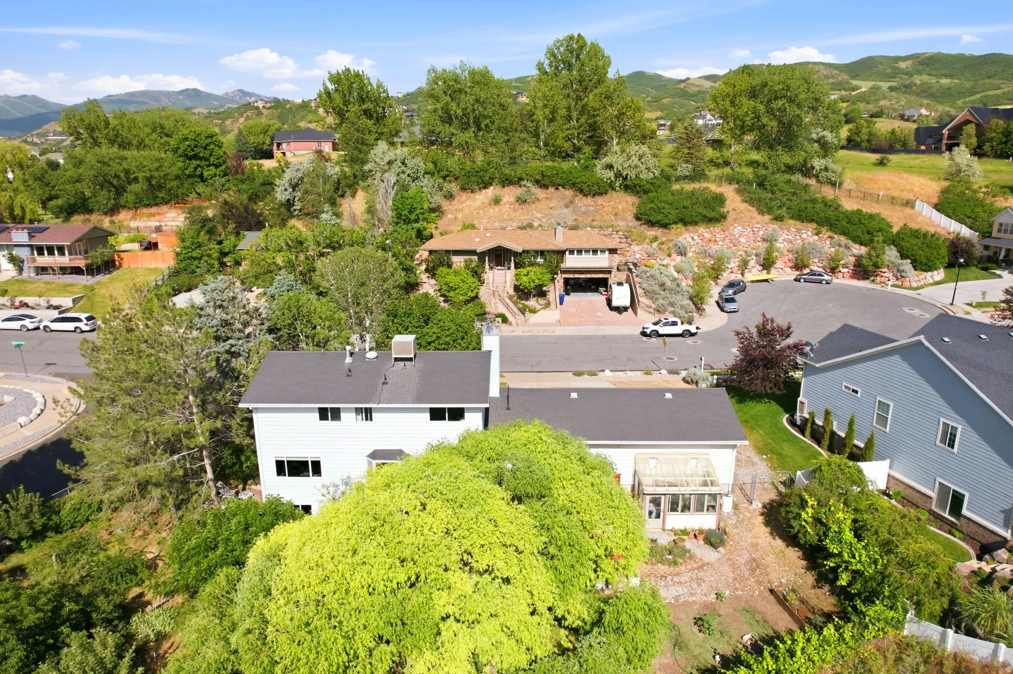 Residential property featuring a white exterior, dark shingle roof, and multiple windows