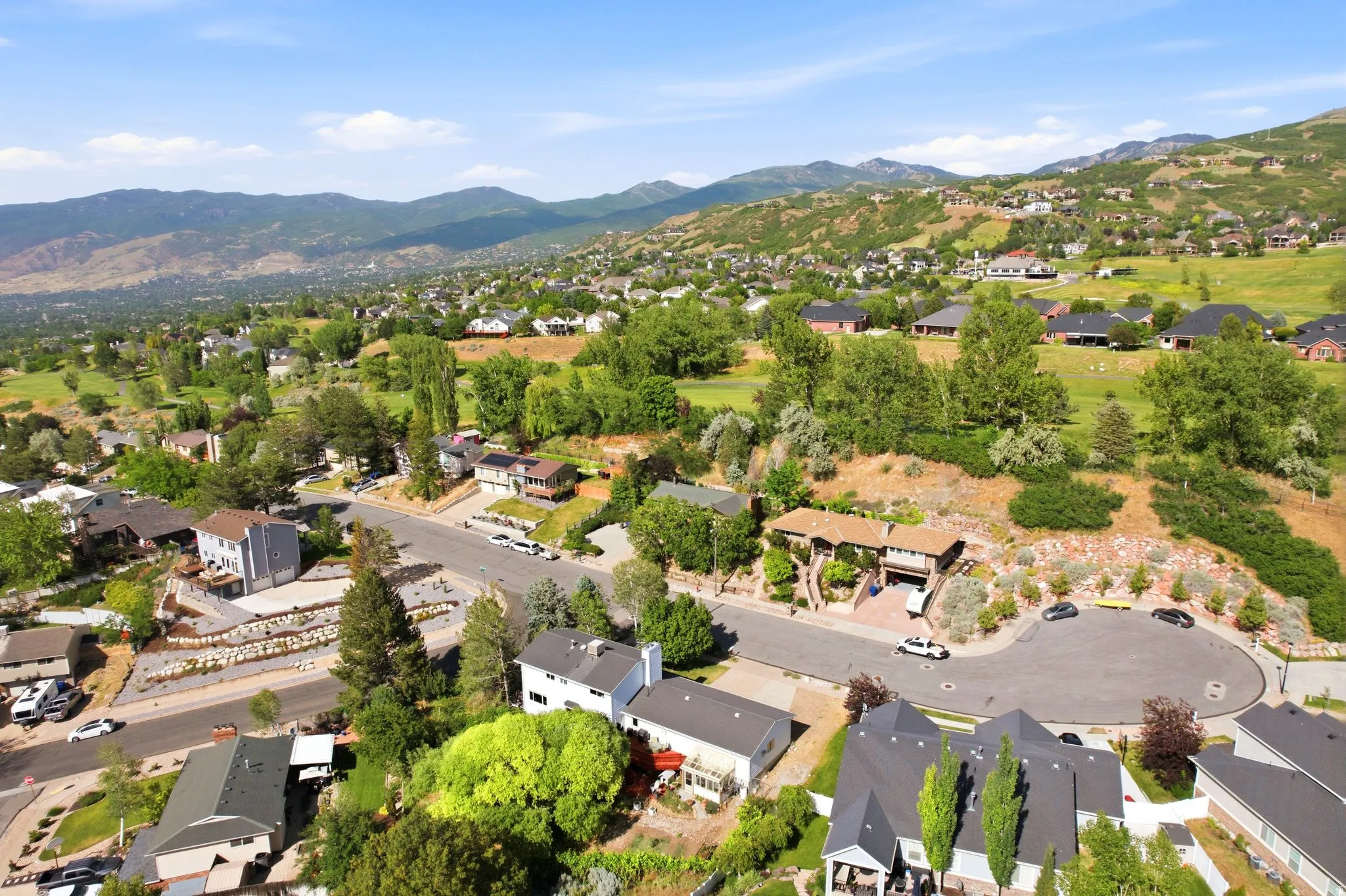 Aerial perspective highlighting a residential community with abundant mature trees and mountainous terrain