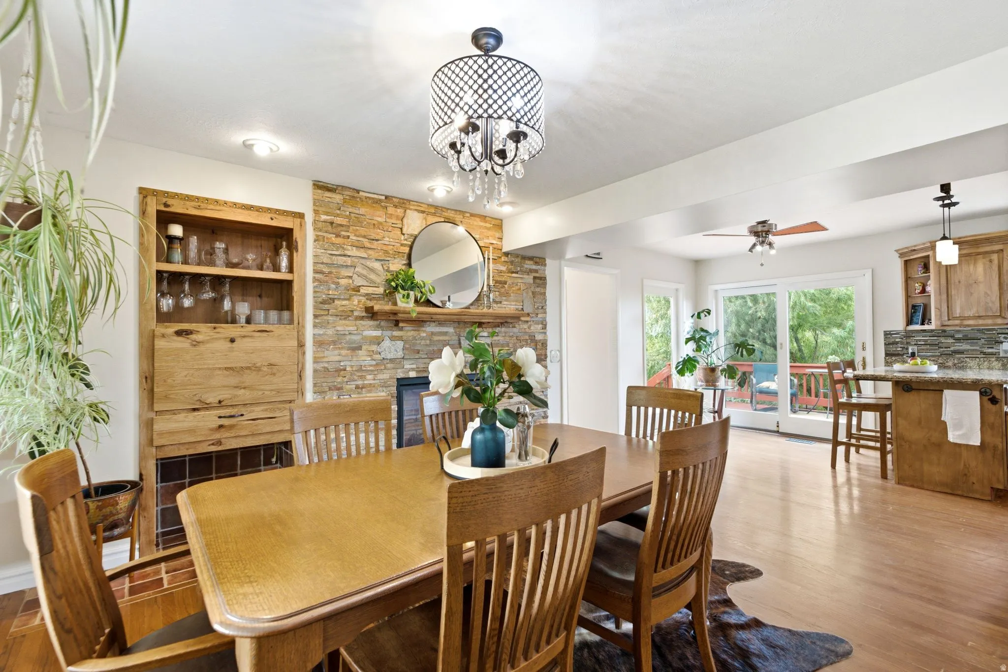 Dining area featuring a stone accent wall with a wood mantel, a built-in wood cabinet with shelving, recessed lighting, and a decorative chandelier