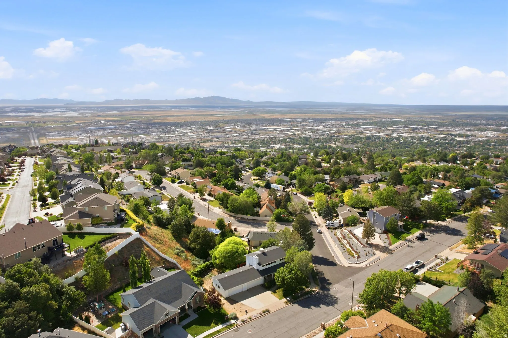 Aerial of North Salt Lake neighborhood featuring a variety of single-family homes, mature trees, and a expansive valley views
