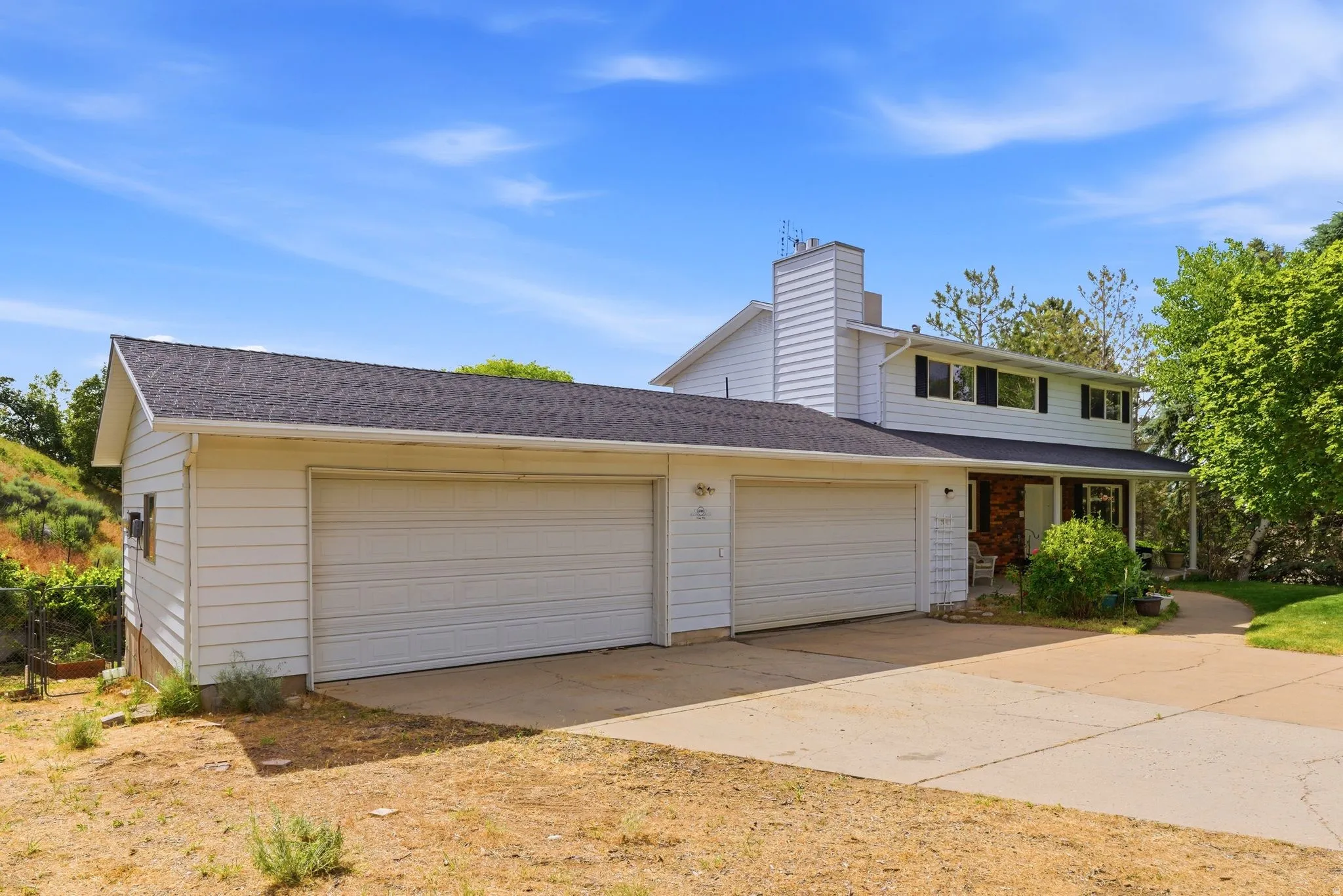 White siding exterior with black roof shingles and an attached four-car garage