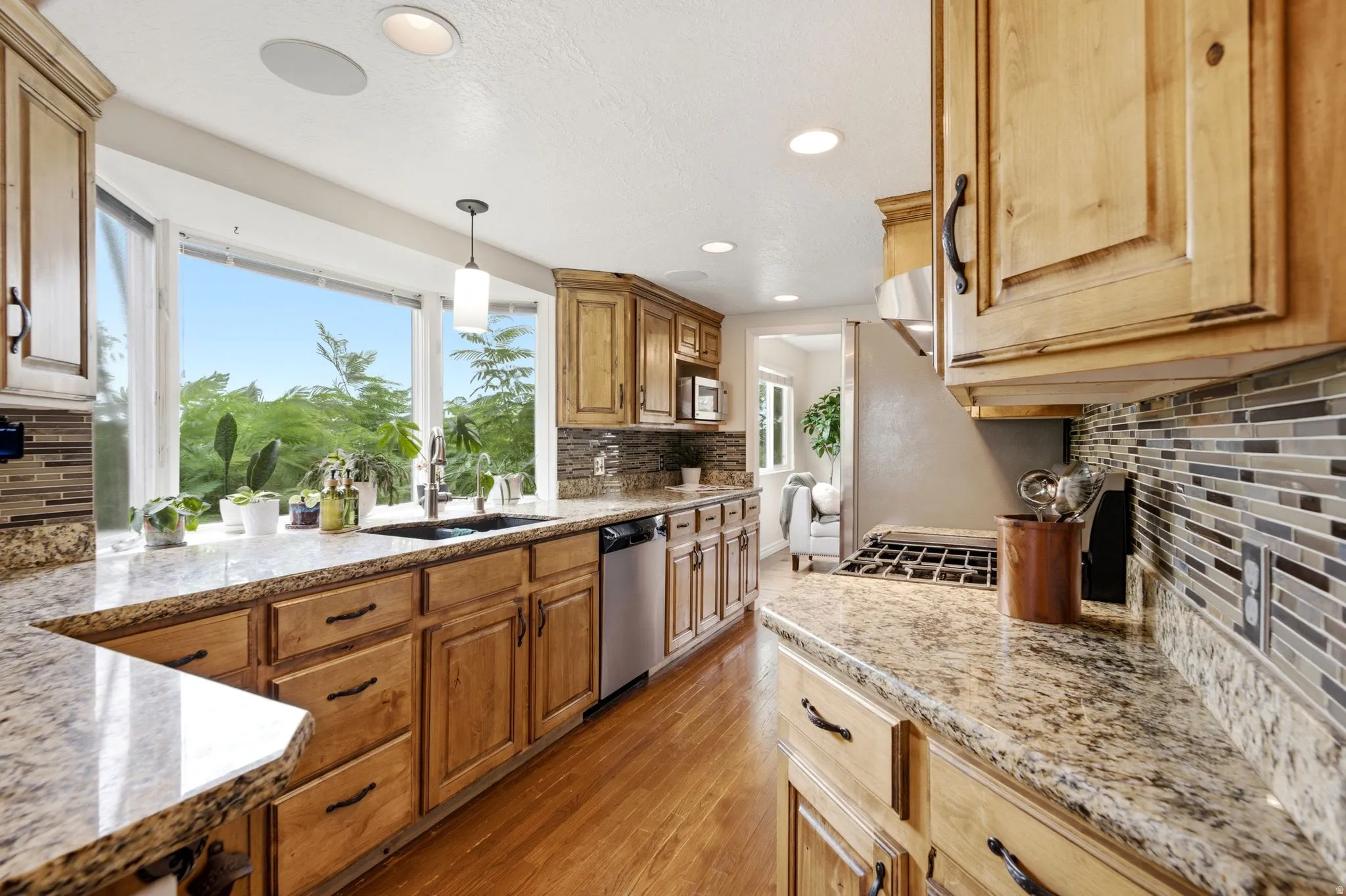 Kitchen featuring light wood cabinetry, granite countertops, and a tiled backsplash