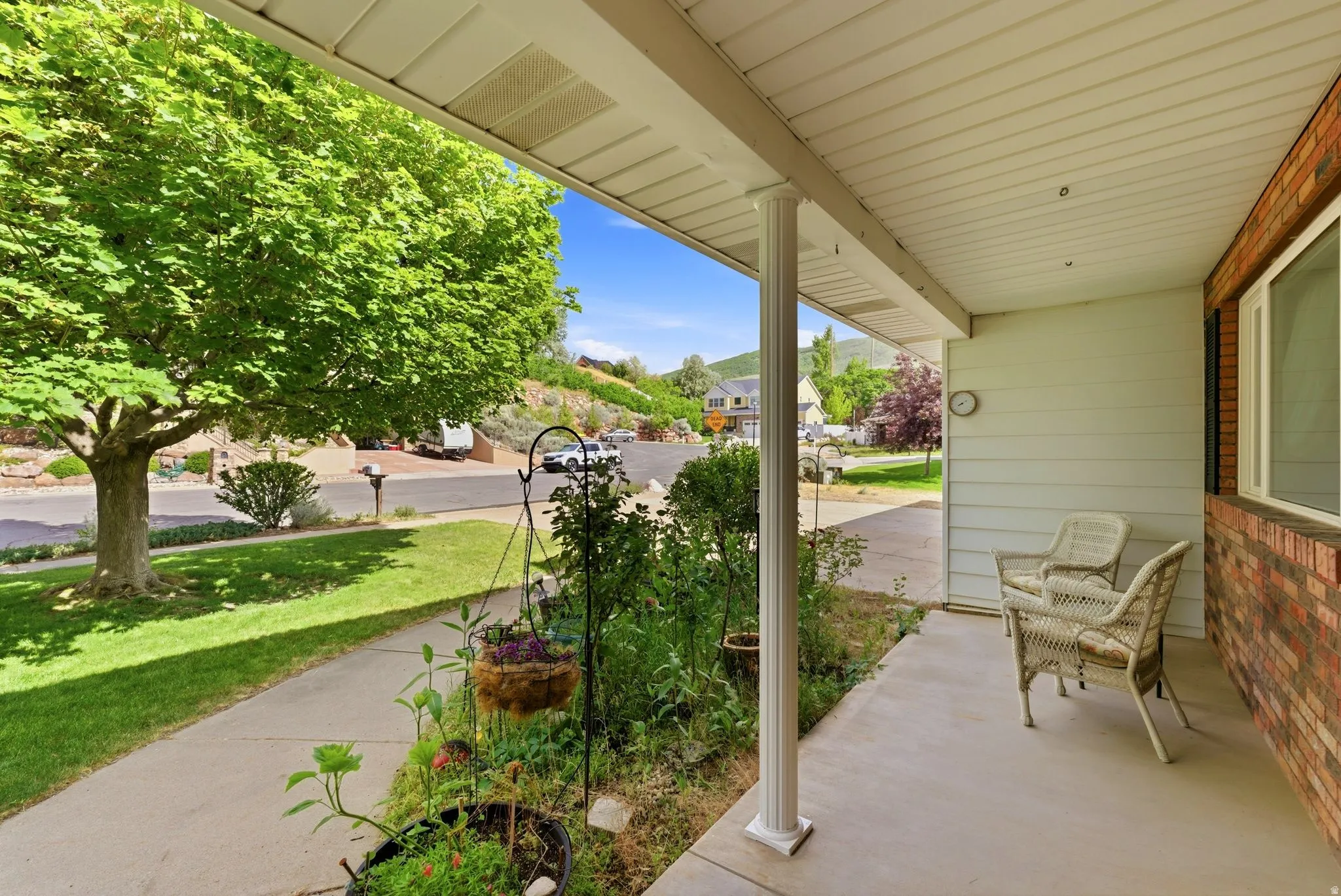 Covered front porch with white siding, brick accents, and a sidewalk leading to a manicured lawn