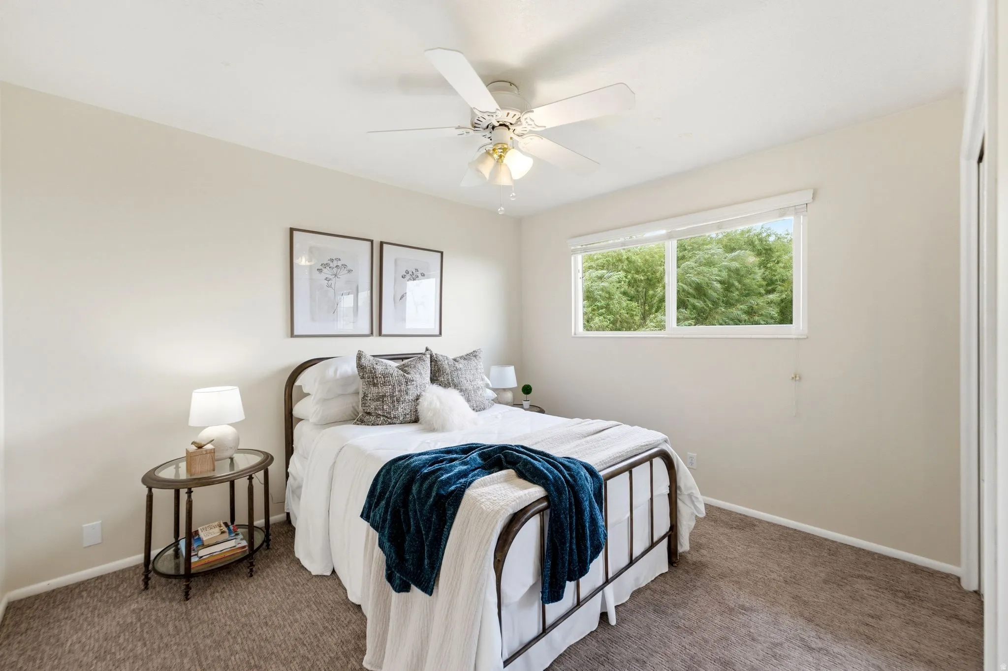 Carpeted room featuring a ceiling fan with integrated lighting, a window with a white frame, and light-colored wall paint