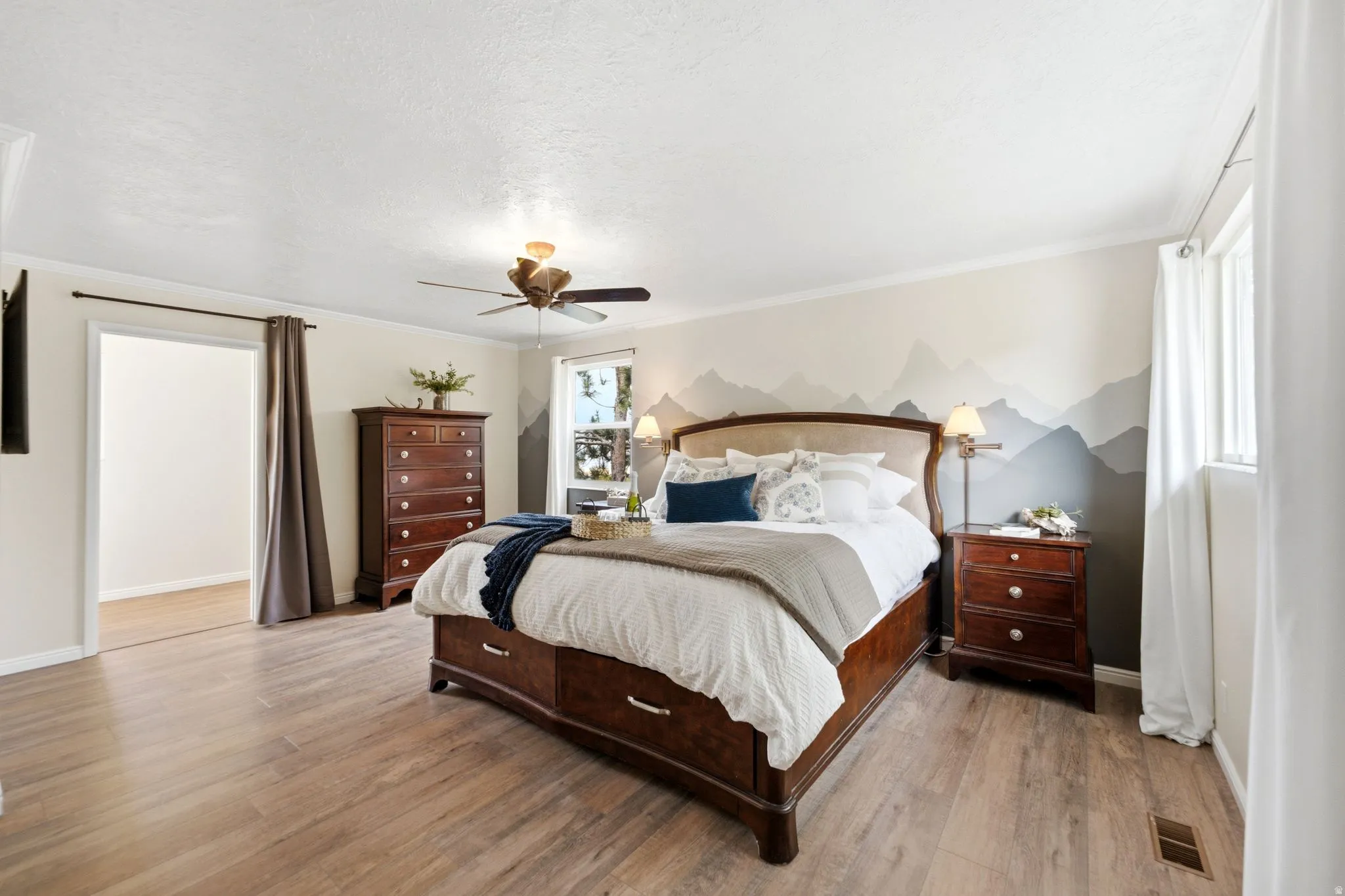 Spacious room featuring wood-finish flooring, a ceiling fan with integrated lighting, and crown molding
