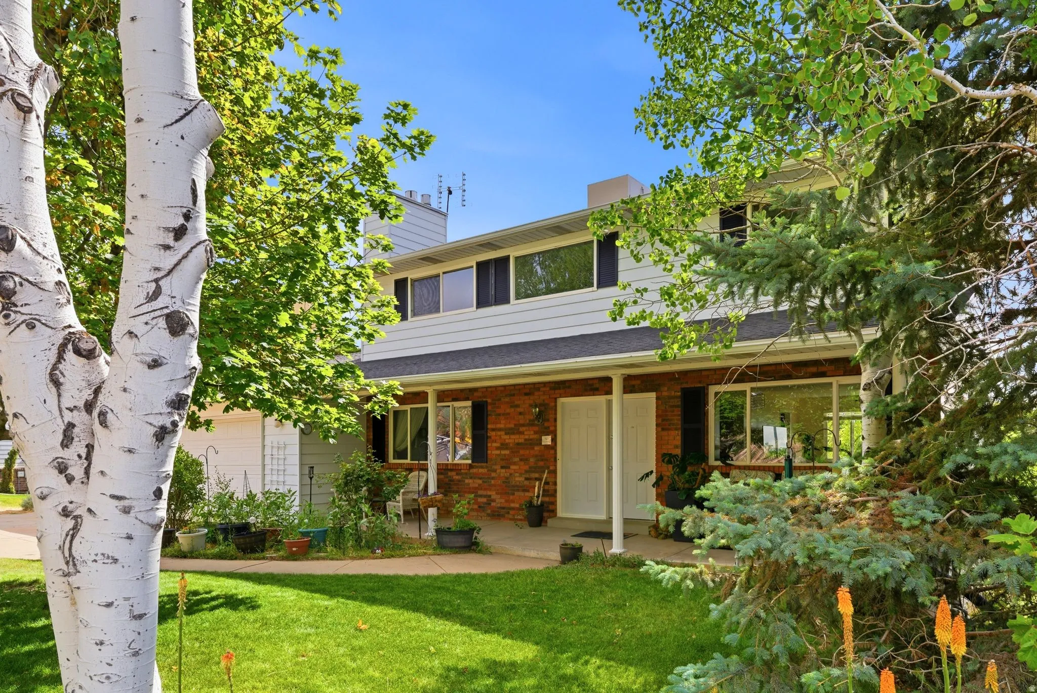 Two-story residence featuring a brick facade with white siding and a covered front porch