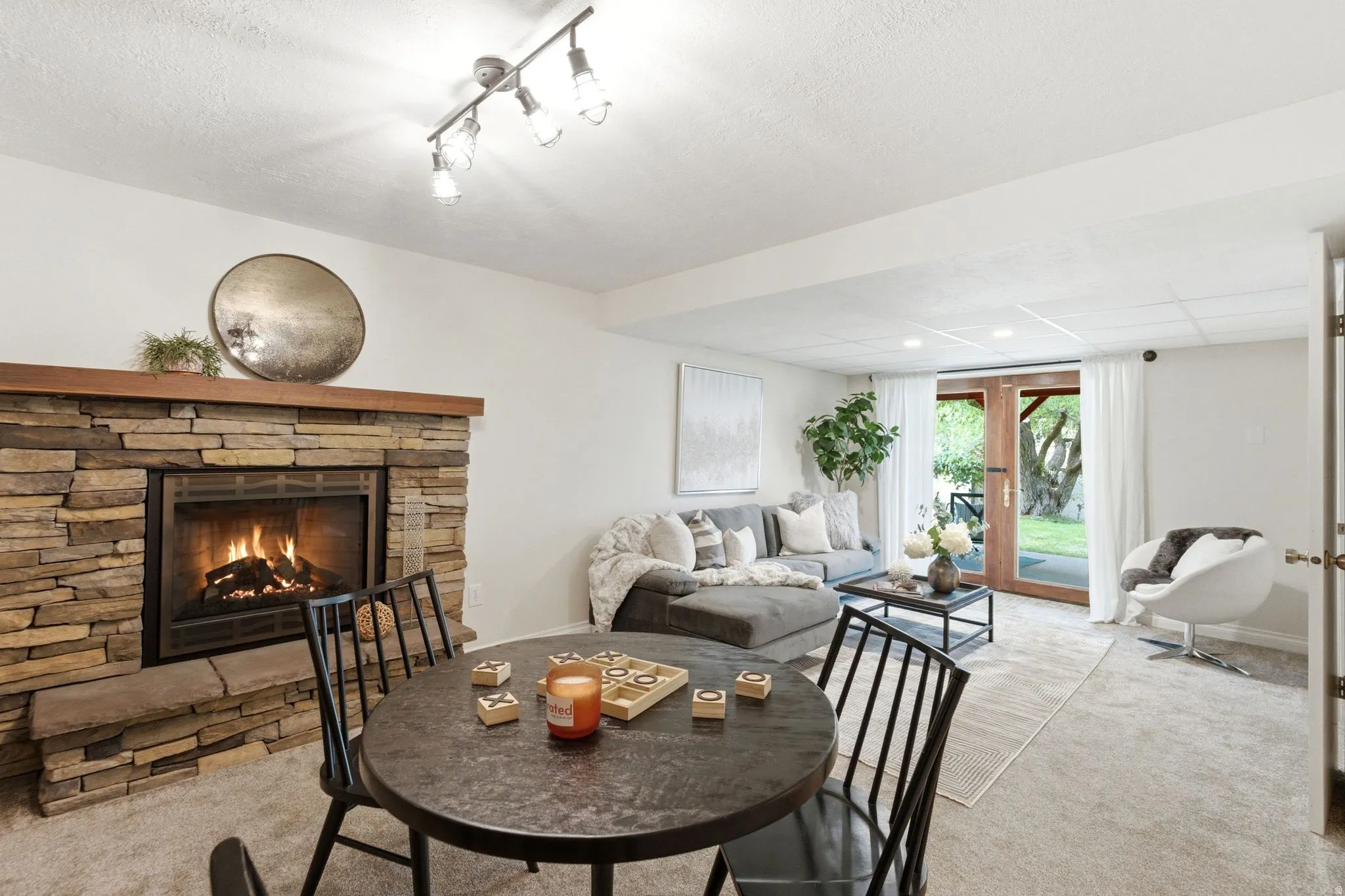 Stone-clad fireplace with a wood mantle, flanked by a seating area with track lighting and a separate dining area