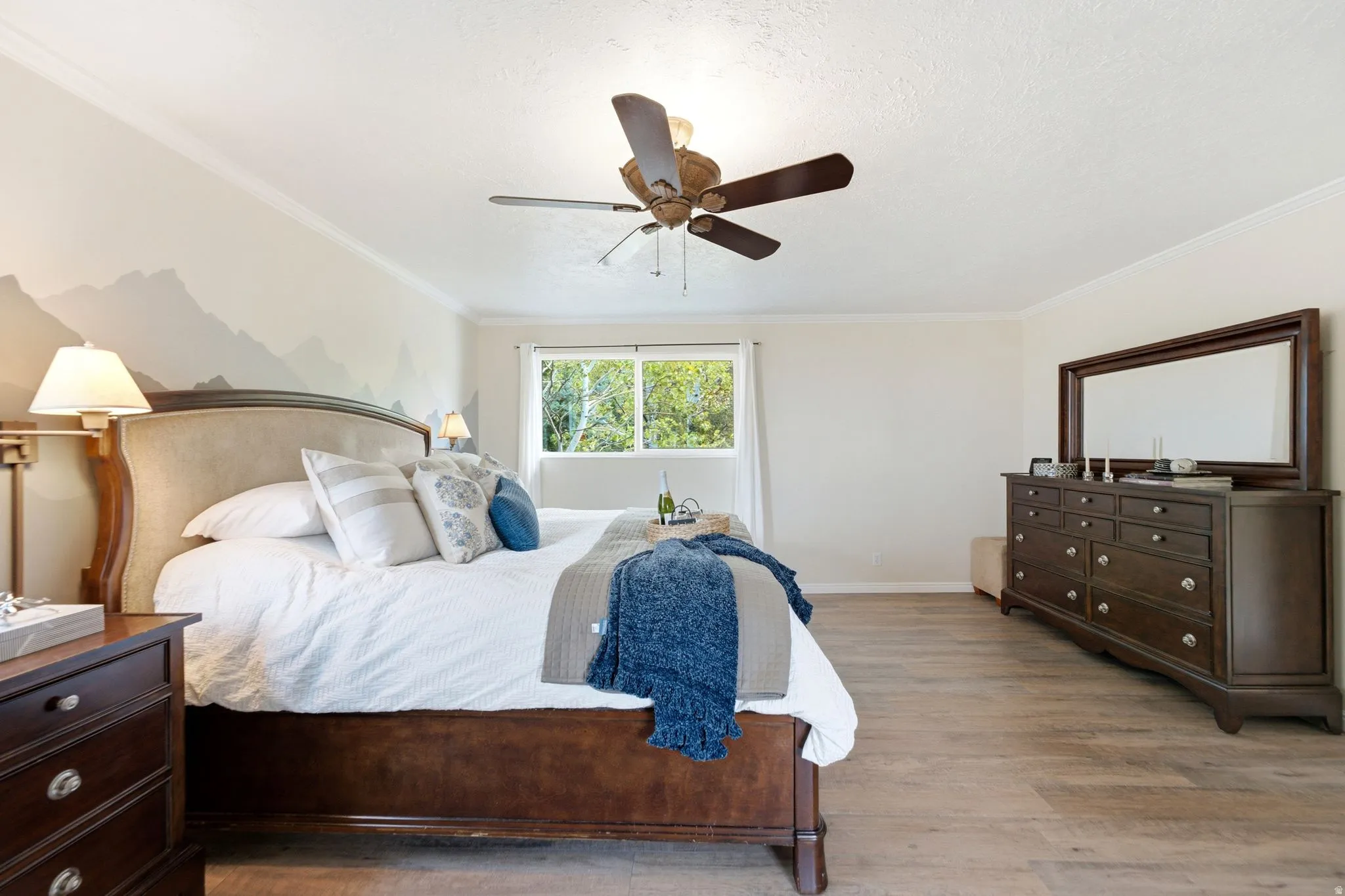Room with wood-finish flooring, crown molding, and a ceiling fan
