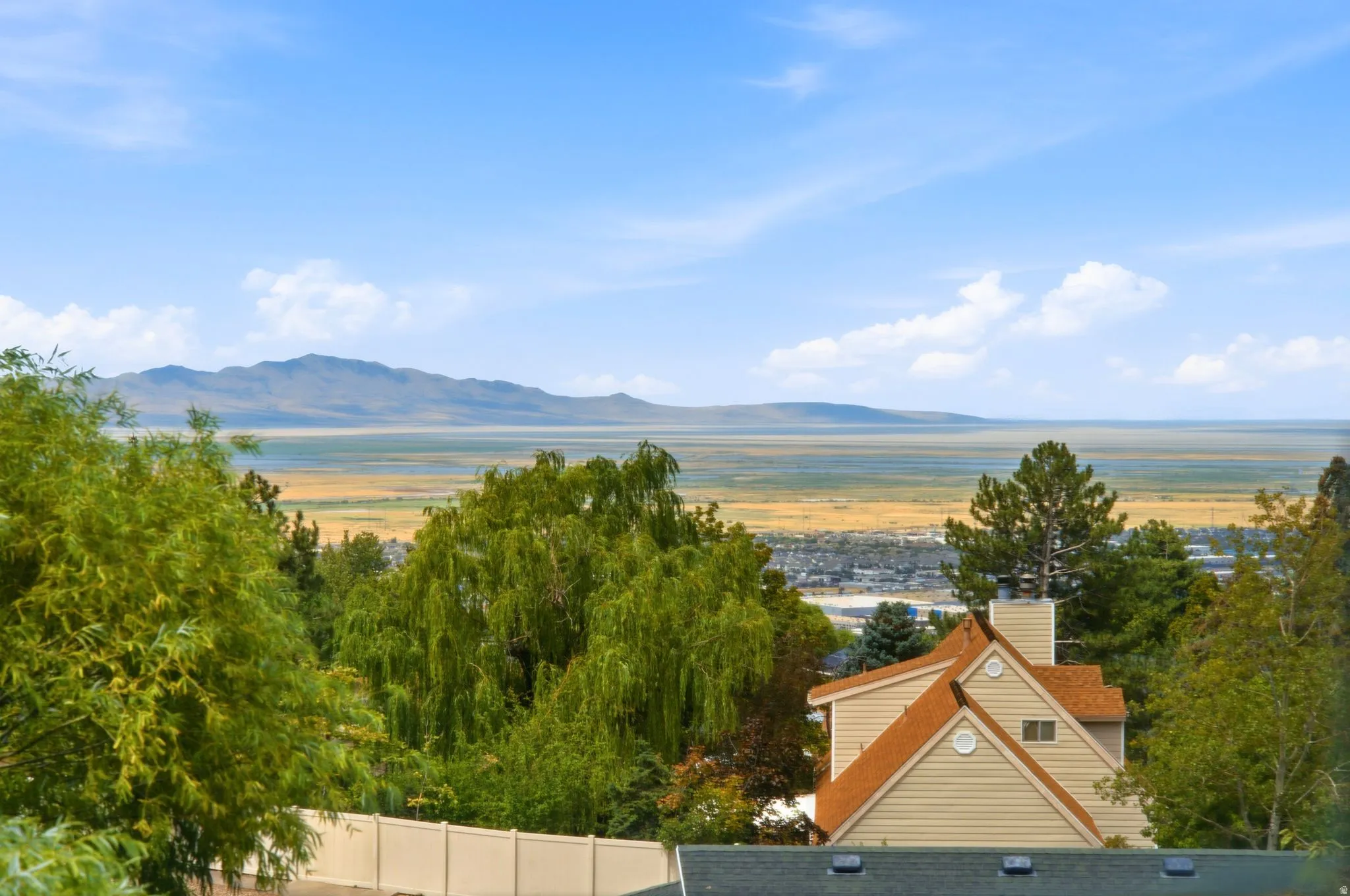 Expansive landscape featuring distant mountains and a large body of water under a clear blue sky