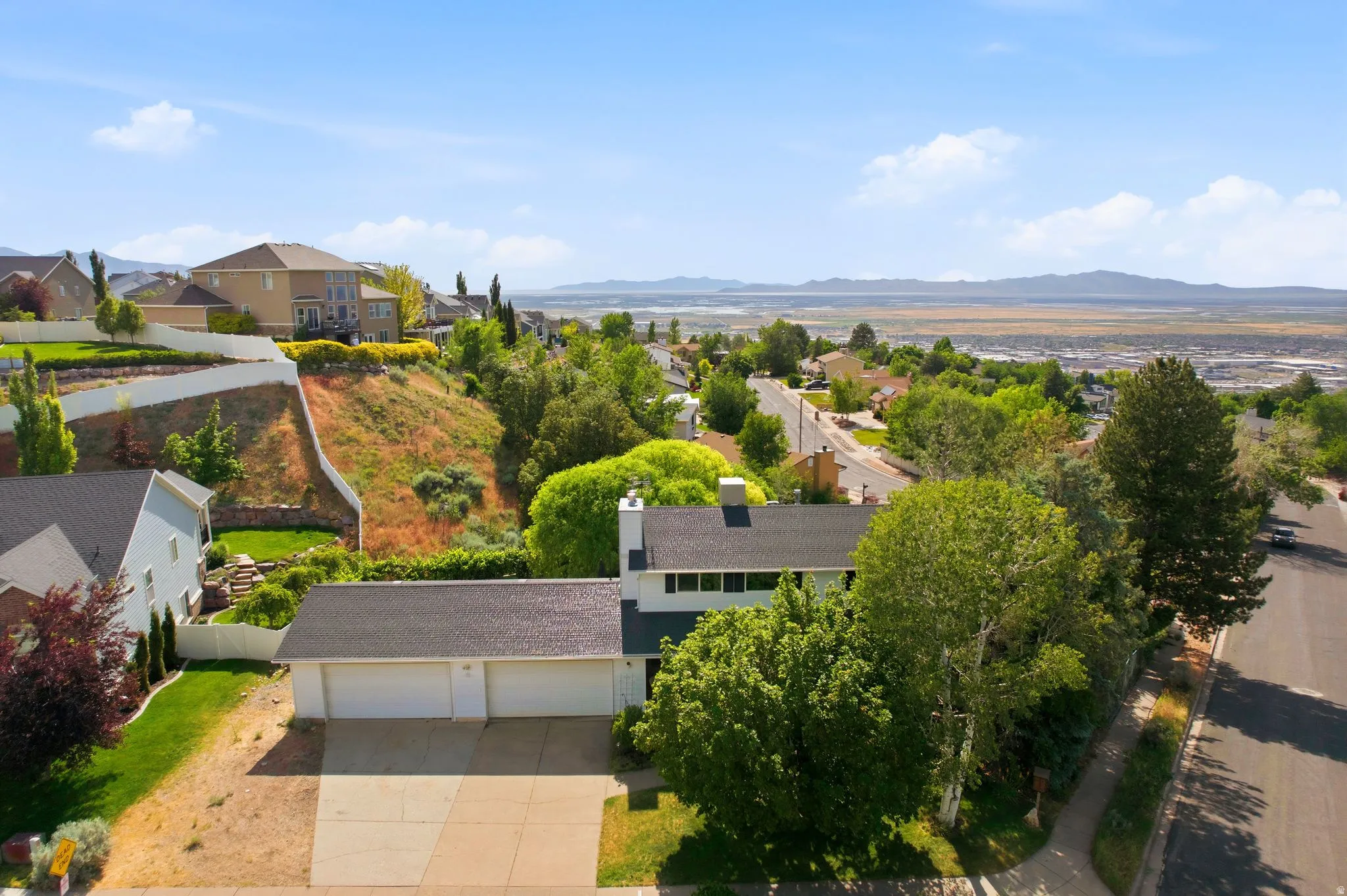 Aerial perspective showcasing a residential property with a multi-car garage and a paved driveway