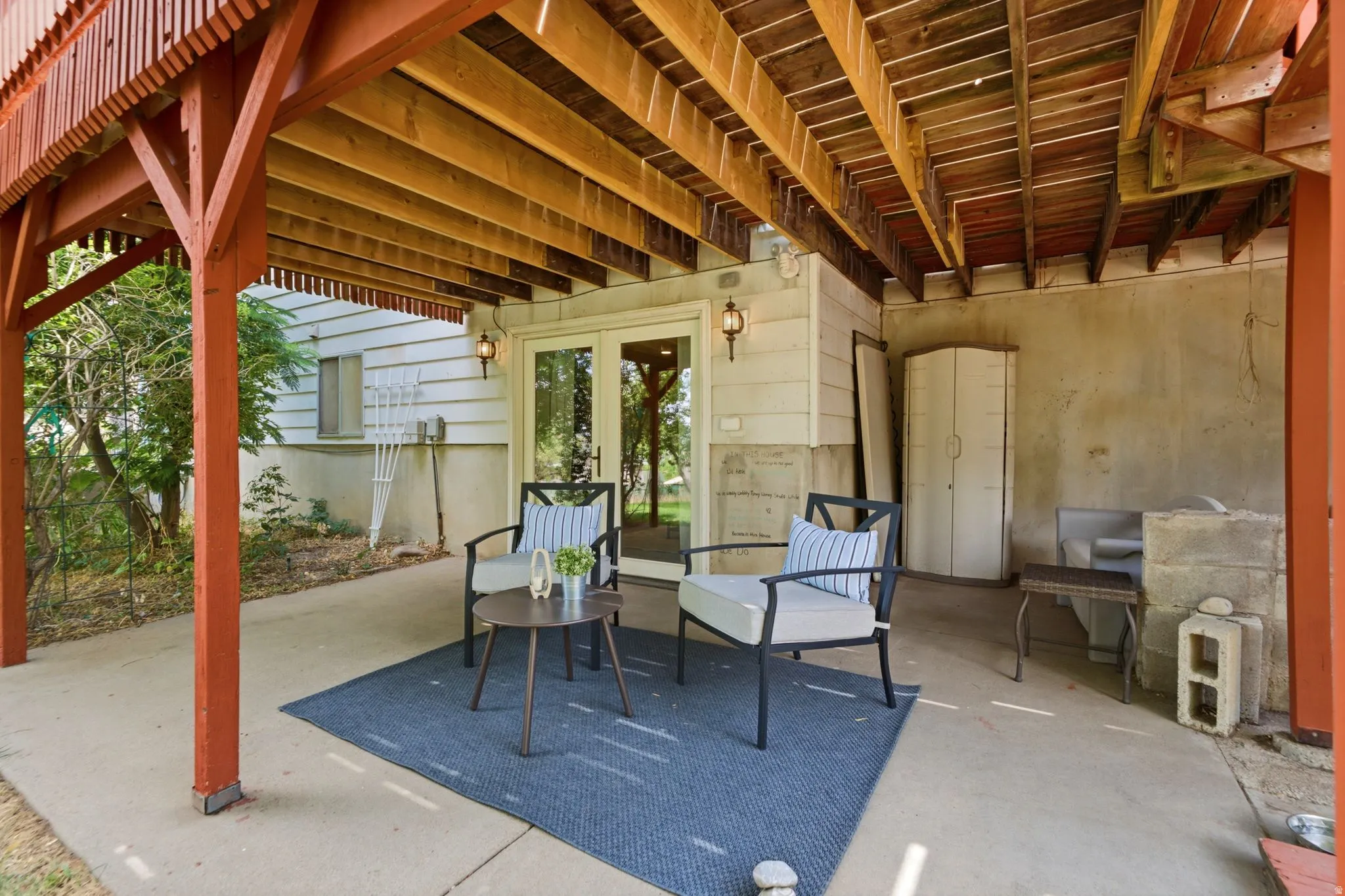 Covered concrete patio space featuring a finished wood deck structure above