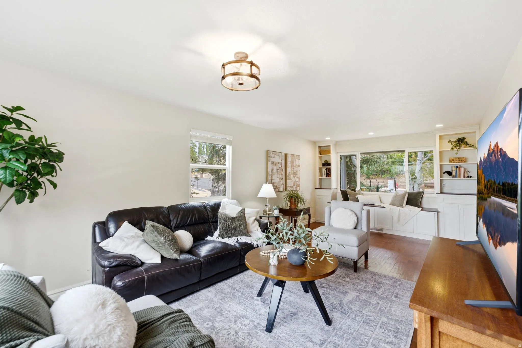 Living area featuring wood-finish flooring and a central window with integrated window seat and storage