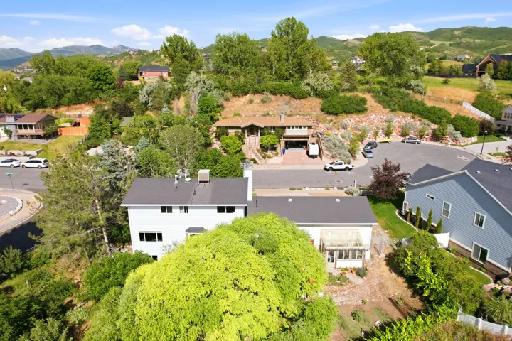 Residential property featuring a white exterior, dark shingle roof, and multiple windows