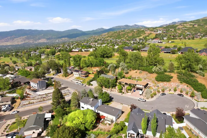 Aerial perspective highlighting a residential community with abundant mature trees and mountainous terrain