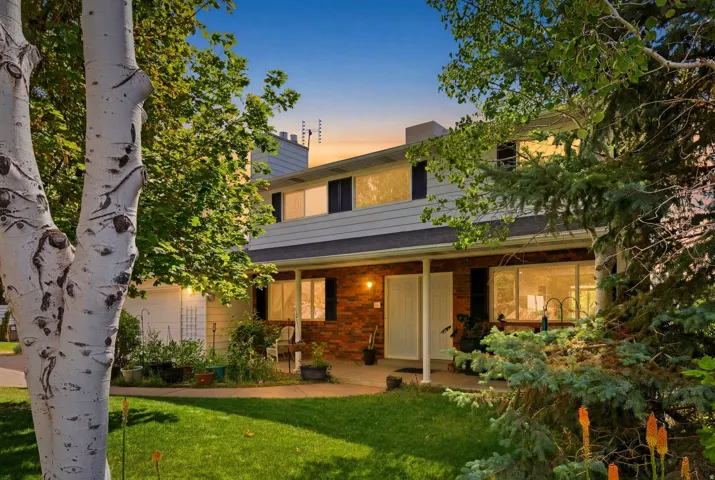 Two-story residence featuring a covered front porch, brick facade, and mature landscaping