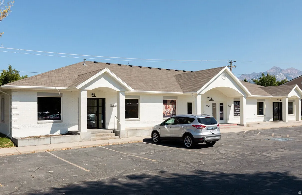 Commercial building with a white brick exterior and a brown shingle roof