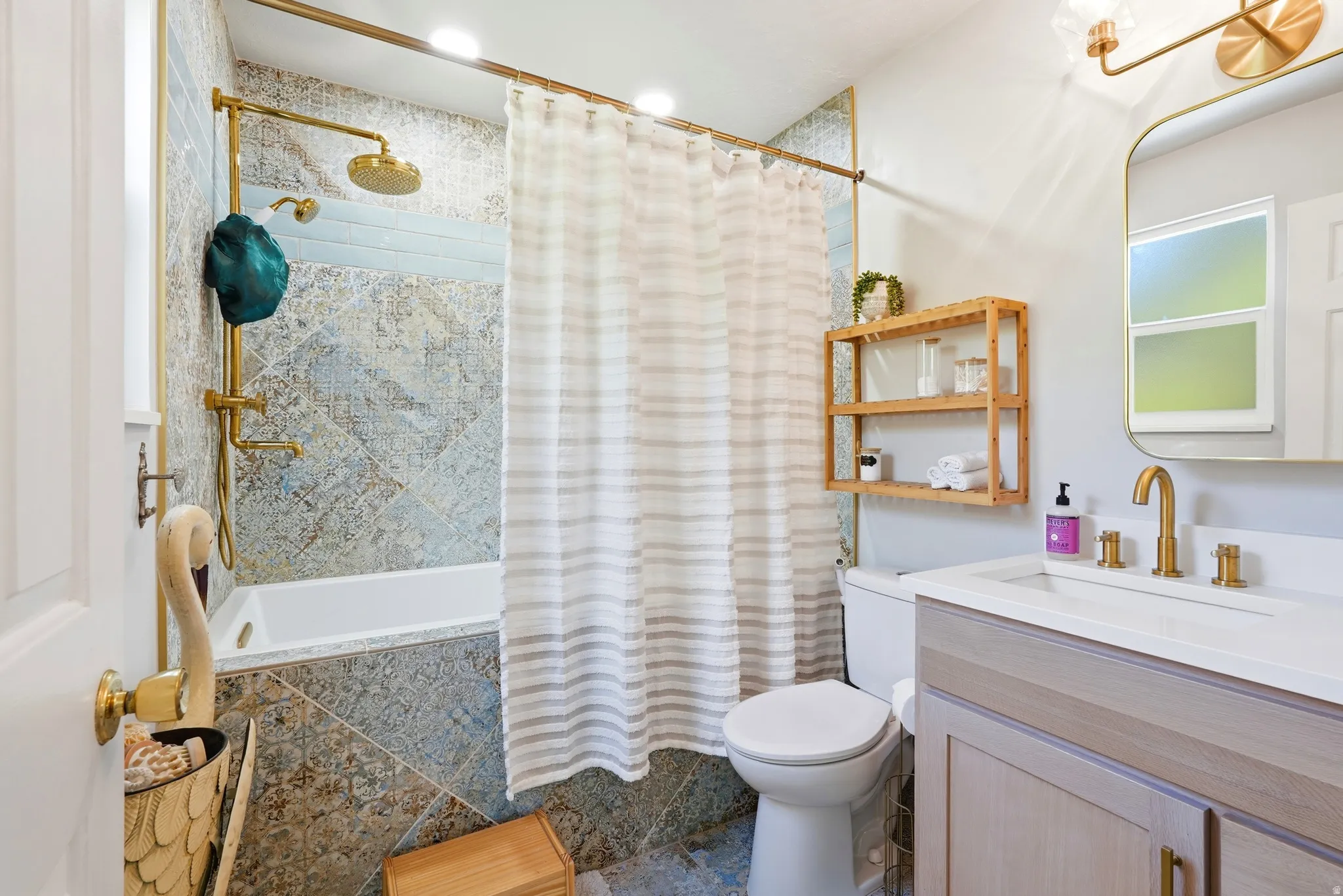 Primary Bathroom featuring a full vanity with a rectangular basin, brushed brass fixtures, and a framed mirror