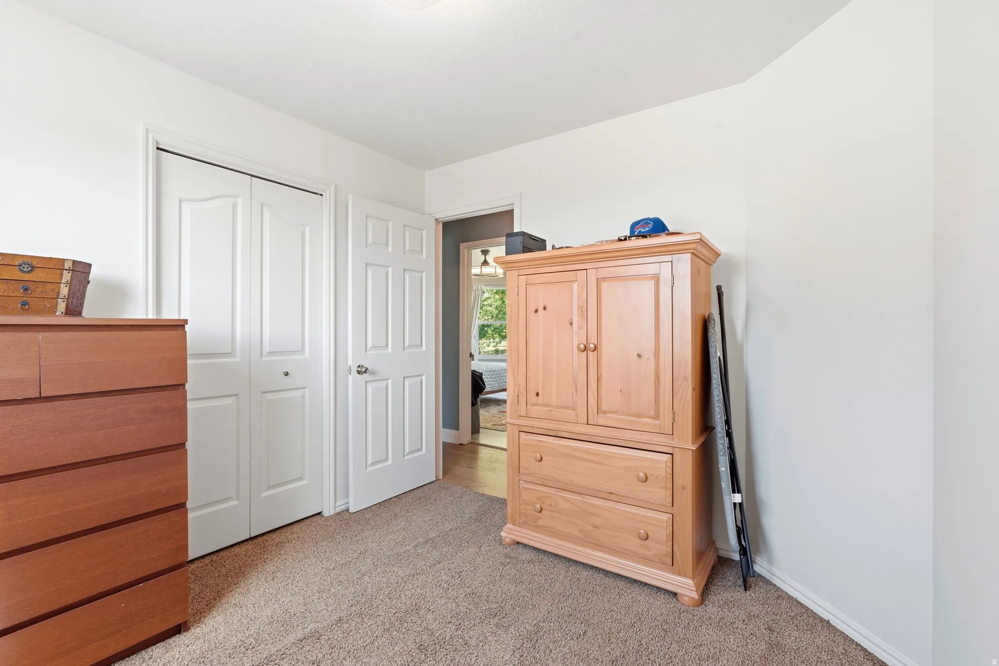 Carpeted room featuring a double bifold closet door and a six-panel interior door with a brushed nickel handle