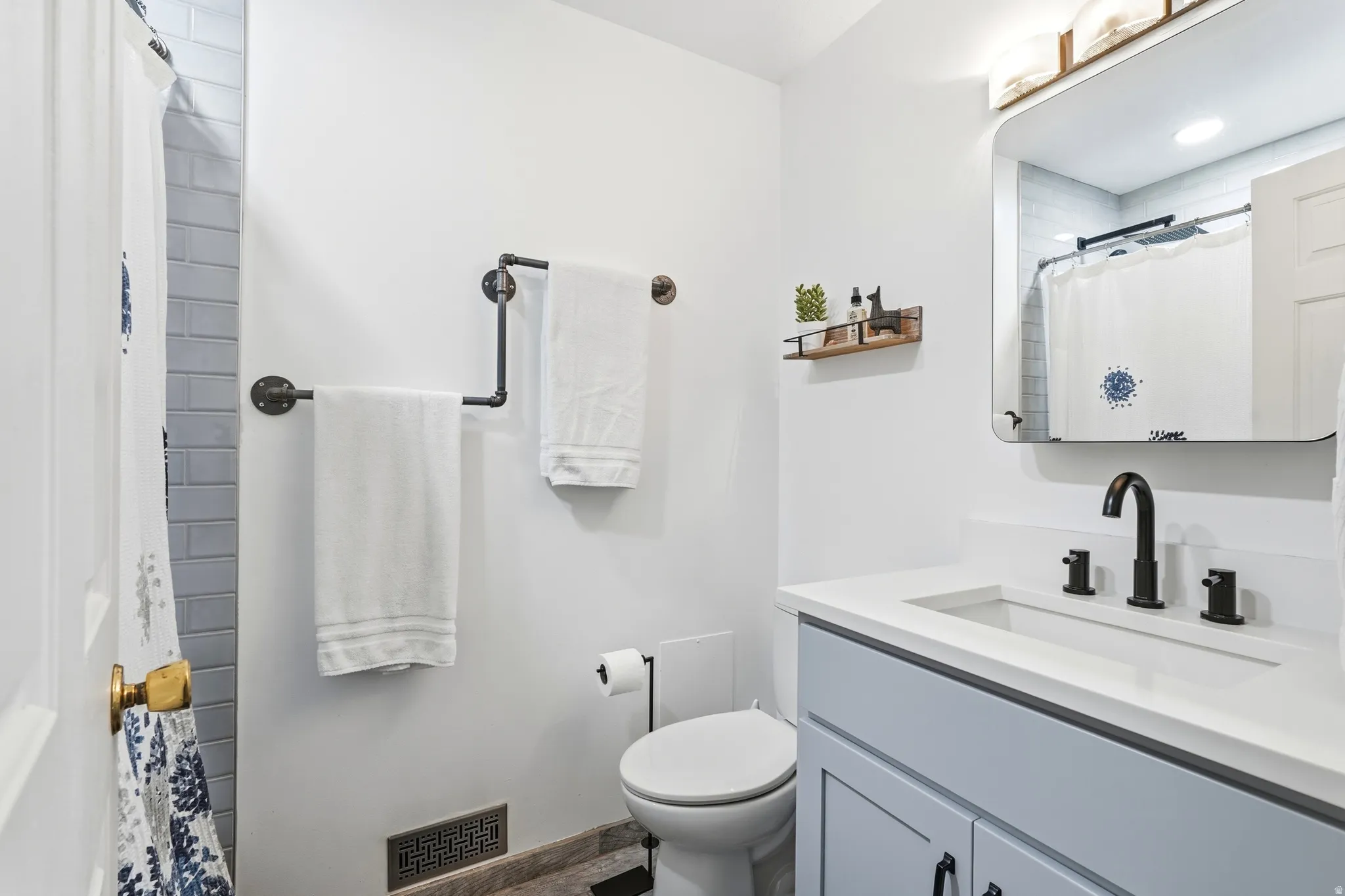 Modern bathroom featuring a light blue vanity with a white countertop and integrated sink, matte black faucet, and a wall-mounted mirror