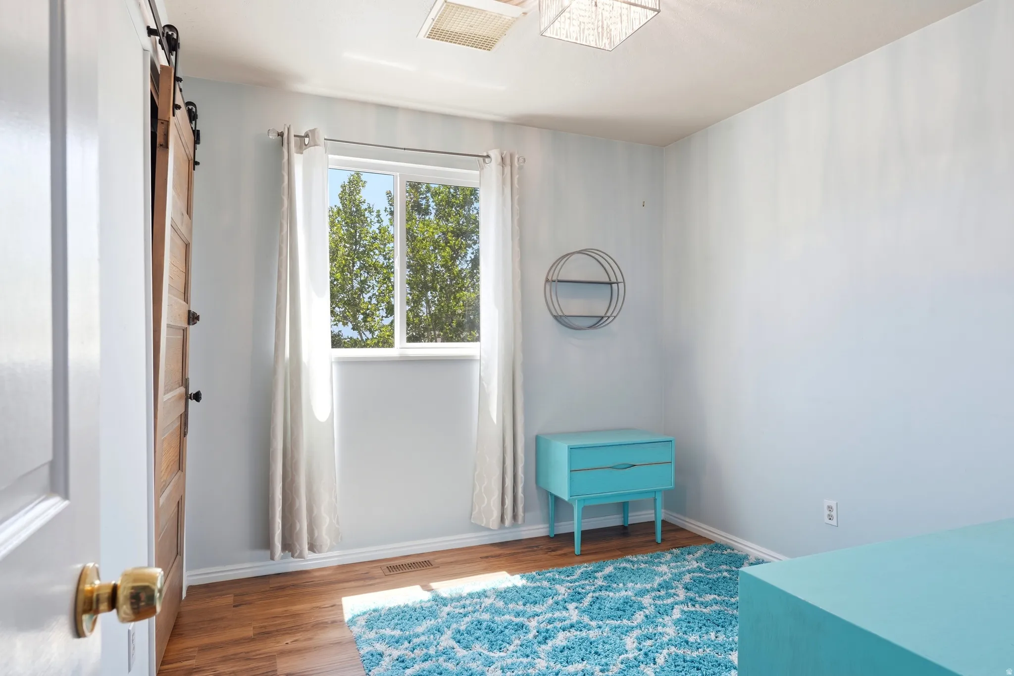 Well-lit room featuring LVP flooring and a window with tree scenery
