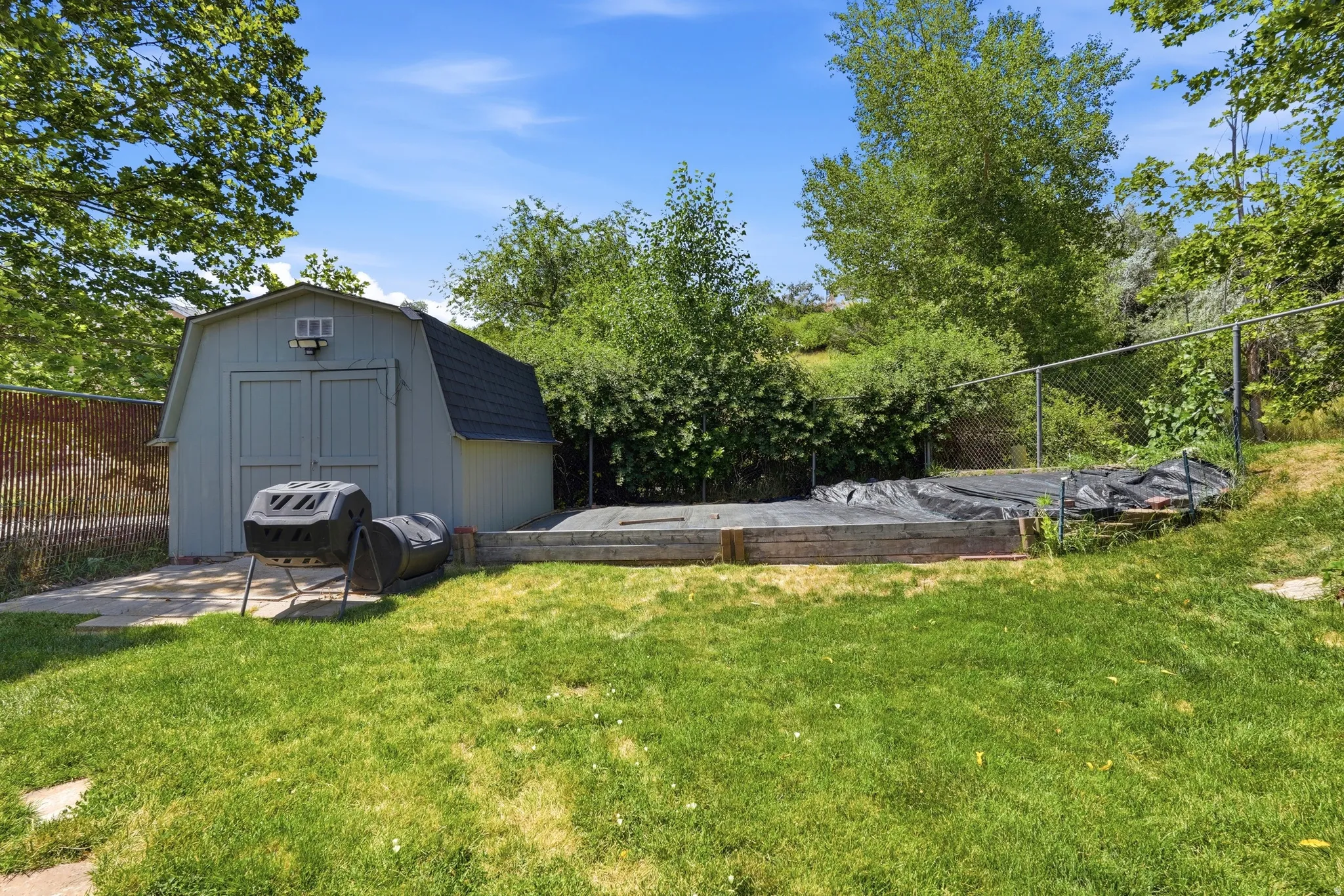 Detached storage shed featuring a gambrel roof and double doors