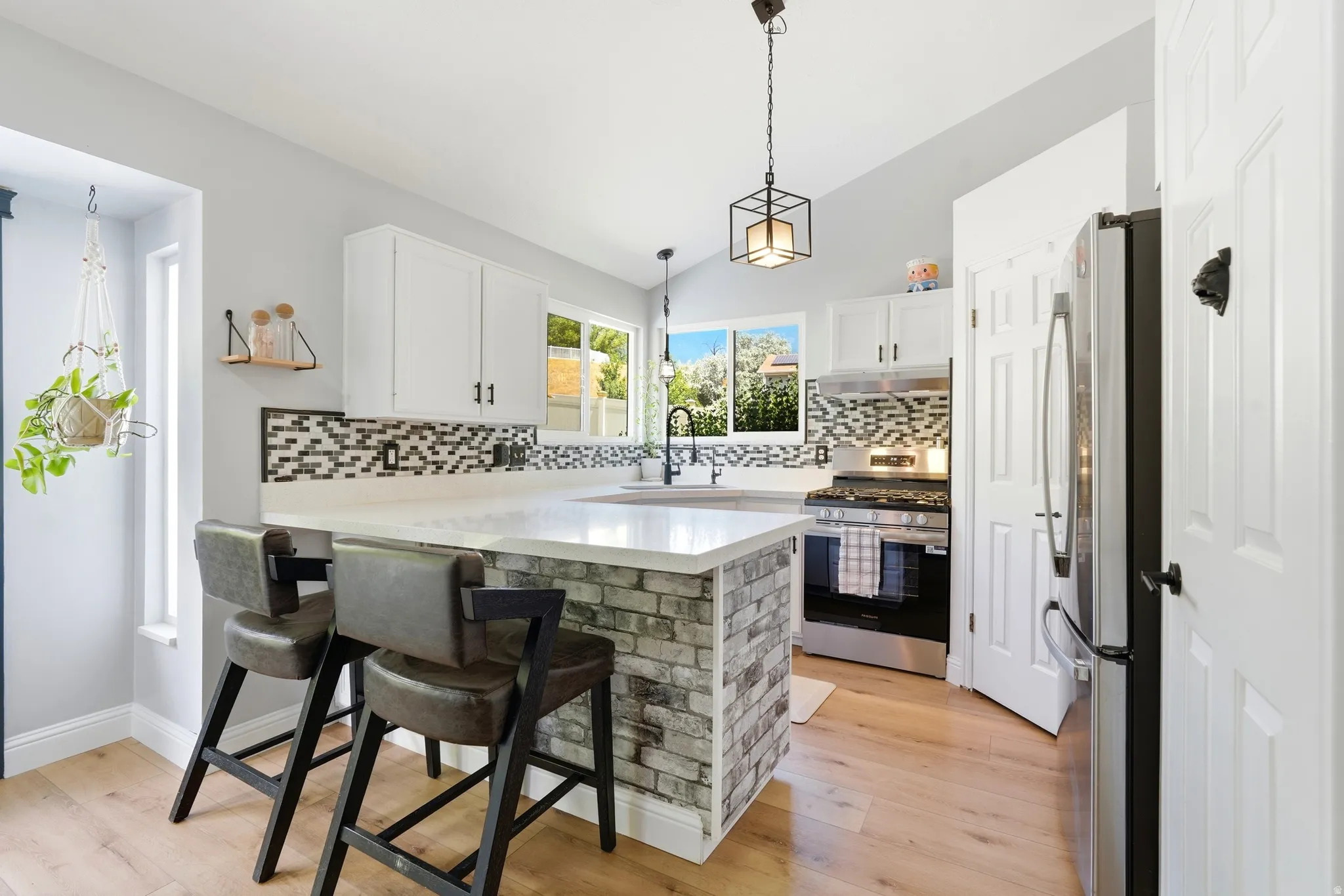 Modern kitchen featuring Quartz countertops, white cabinetry with dark hardware, stainless steel appliances, and LVP Flooring
