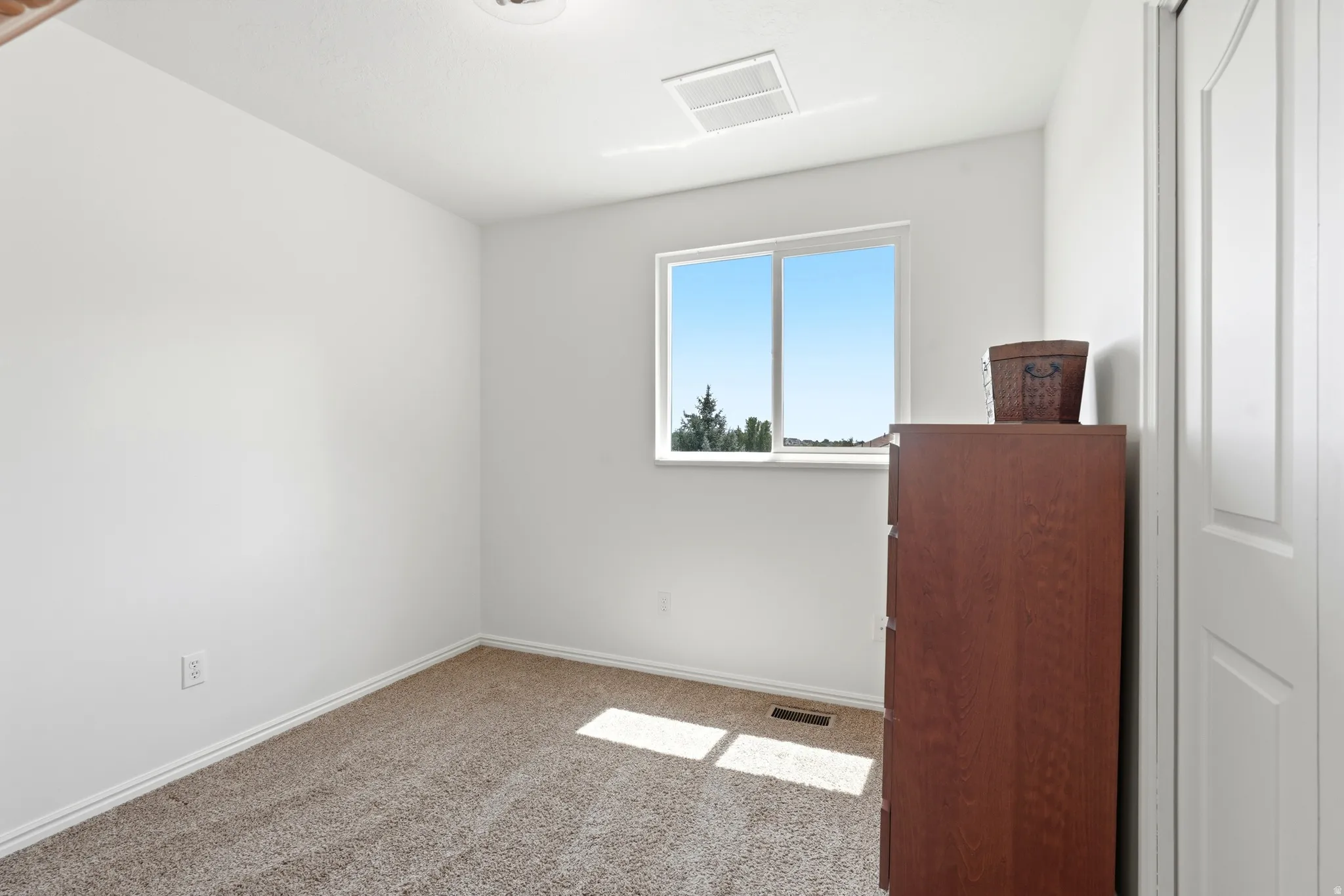 Carpeted room featuring a large window, white trim, and a white paneled door