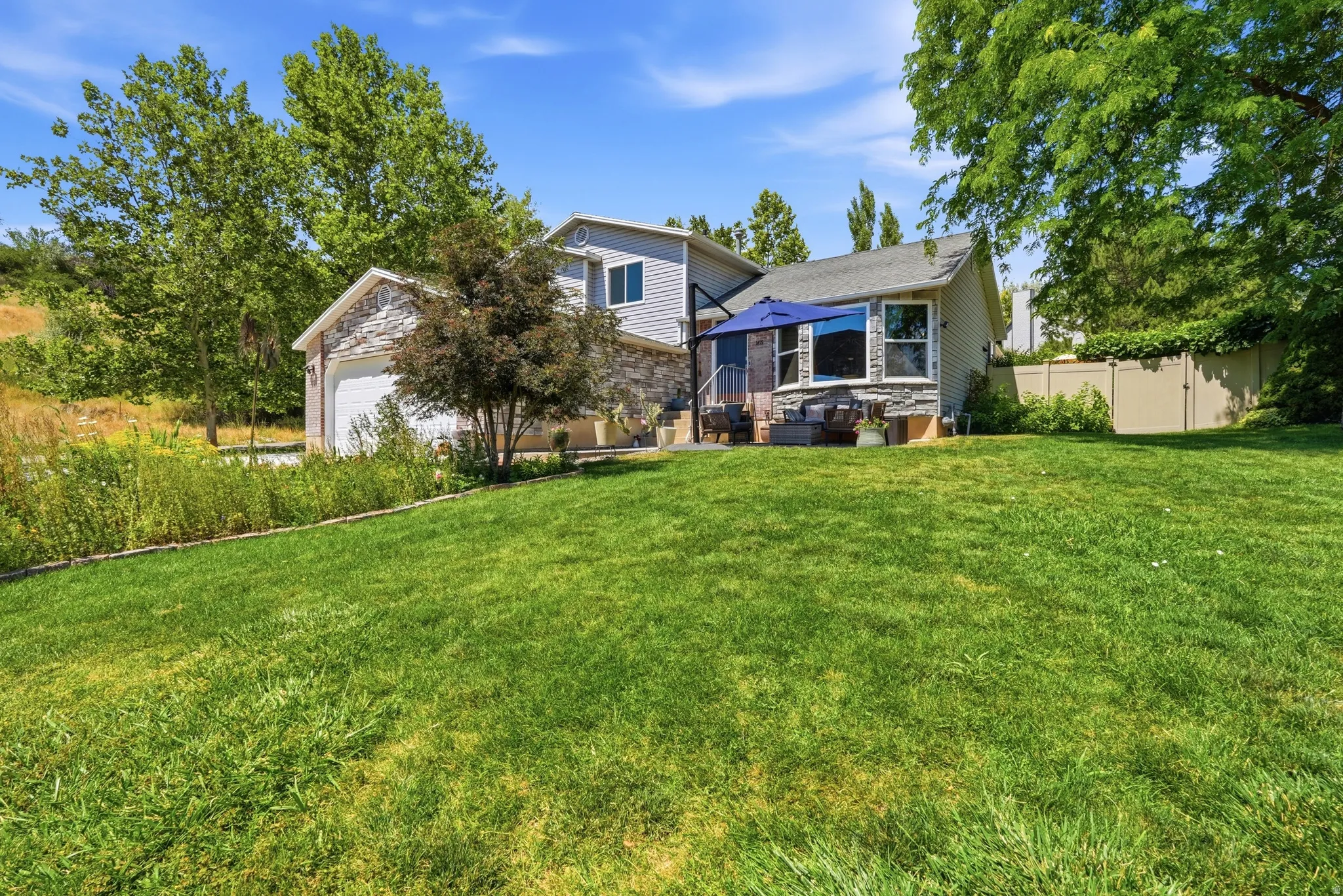 Expansive grassy yard with a stone-clad exterior and bay window