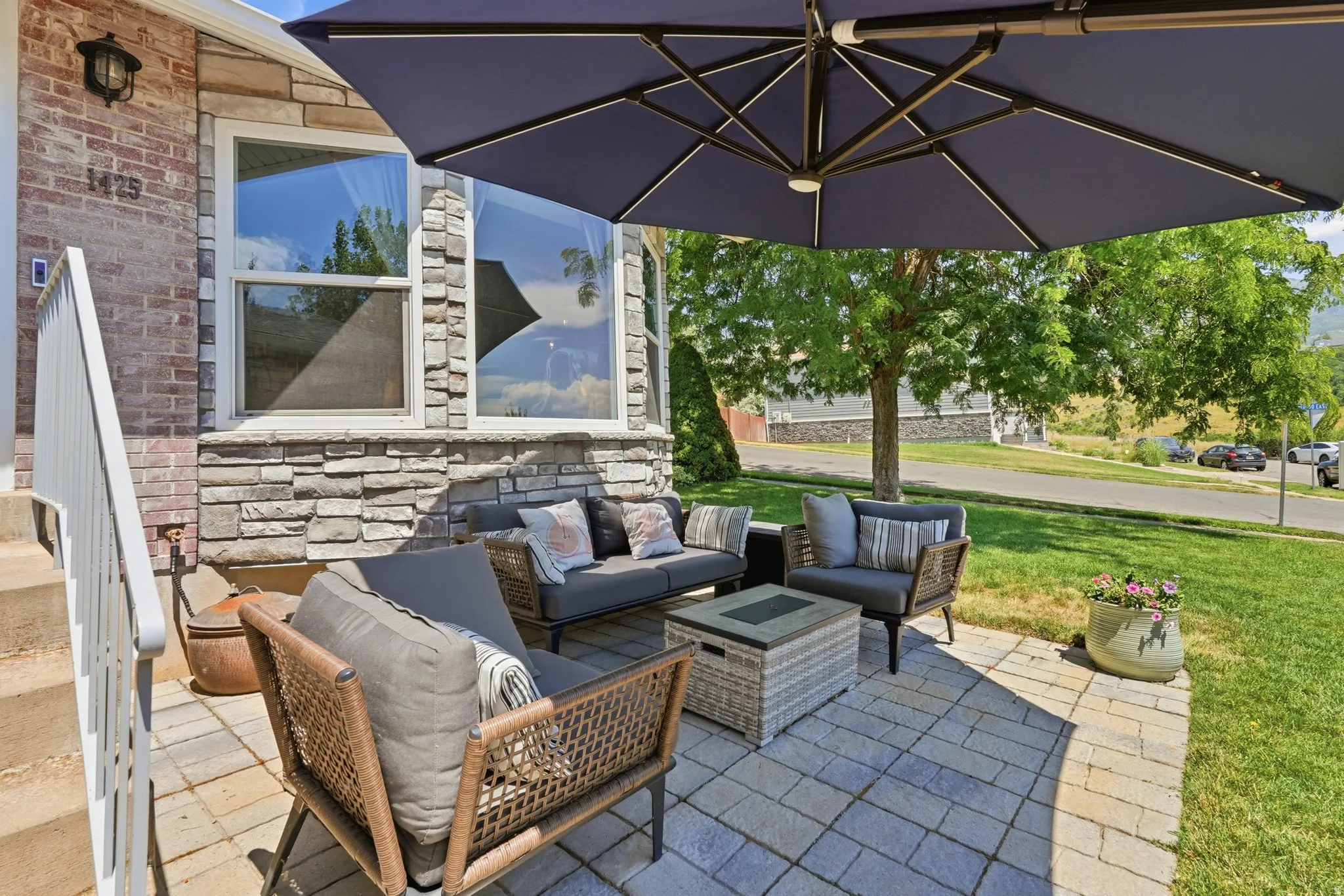 Paved outdoor patio area featuring a stone veneer facade, brick siding, and a manicured lawn