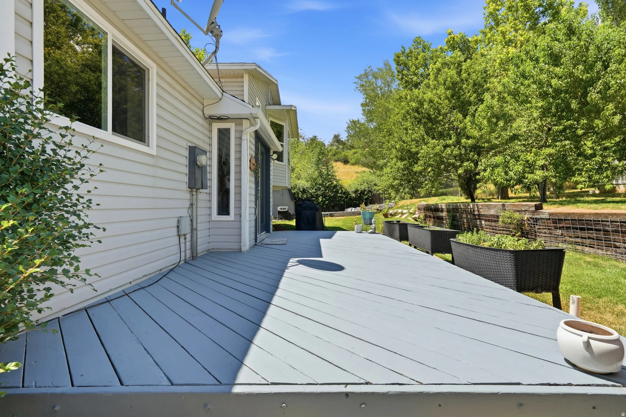 Expansive exterior deck featuring a neutral finish, multiple window placements, and sliding glass door access to the interior
