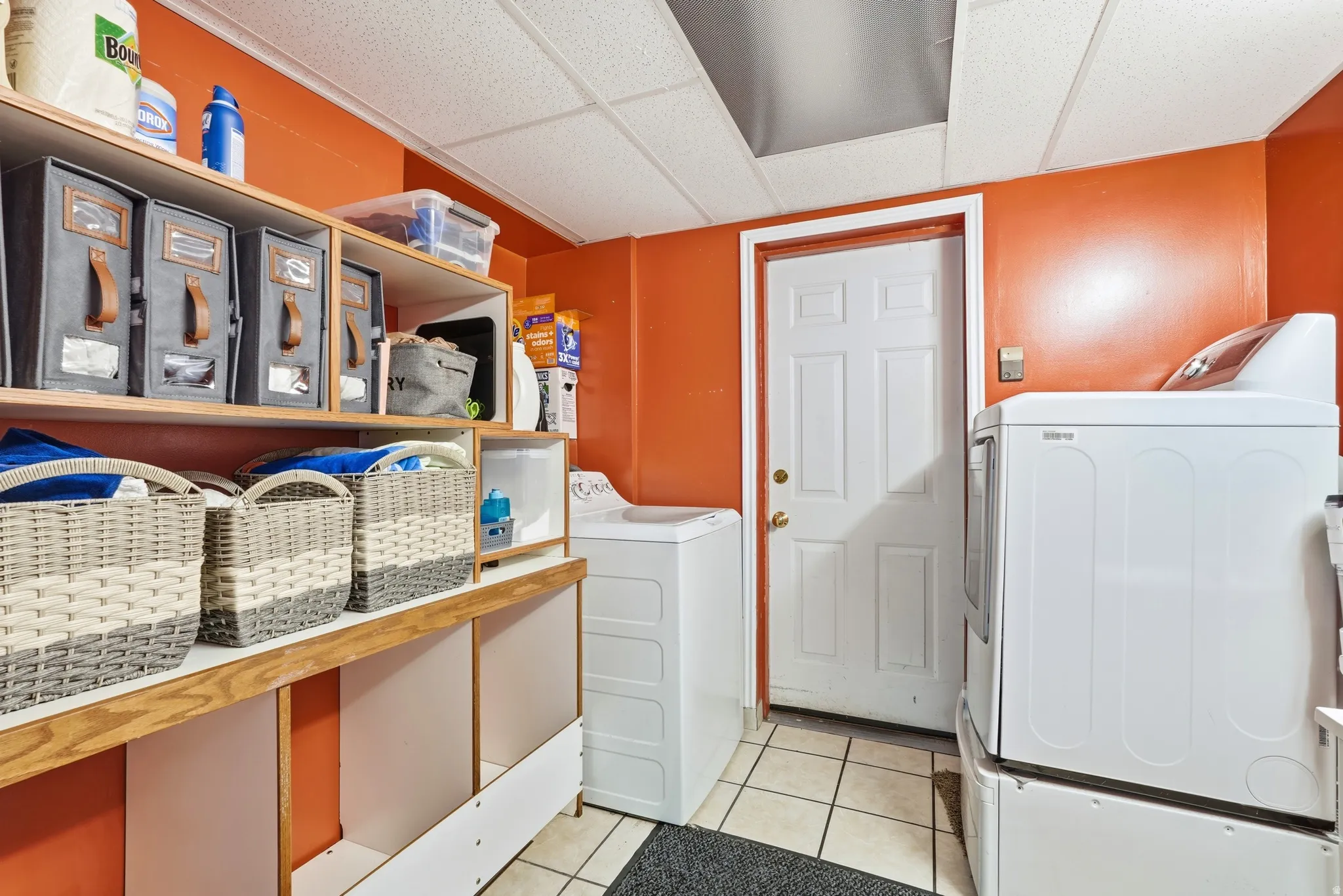 Dedicated laundry area featuring white tile flooring, built-in shelving,.