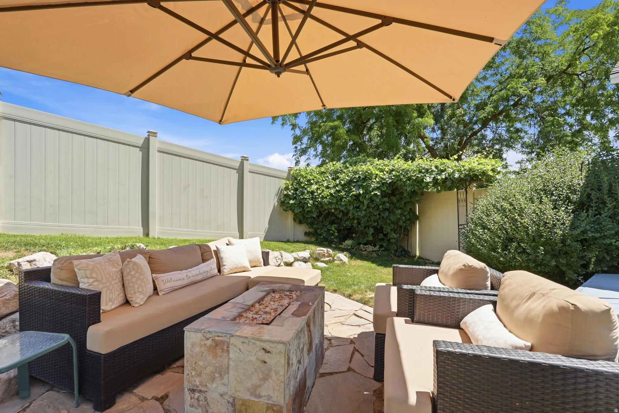 Outdoor patio area featuring flagstone paving, a built-in stone fire pit, and a privacy fence