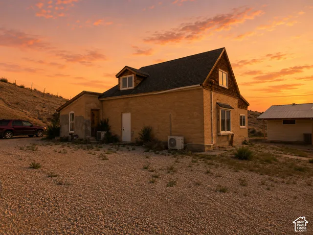 Brick exterior architecture with a dormer window, bay window, and a gravel parking area