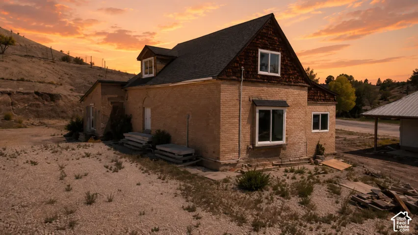 Brick exterior home with a dark shingle roof and dormer windows